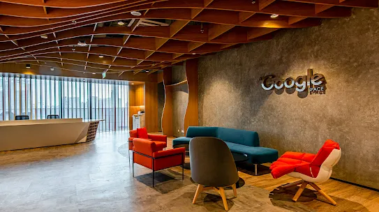 An office lobby with the Google sign, a reception desk and various seating.
