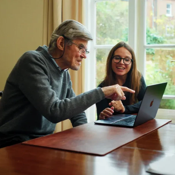 3 people sitting on a table and working together on a computer
