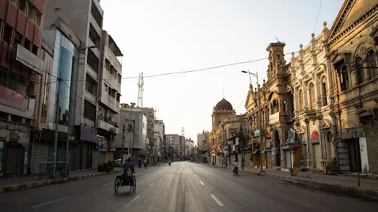 A street with various buildings, and people riding in bikes and other vehicles.