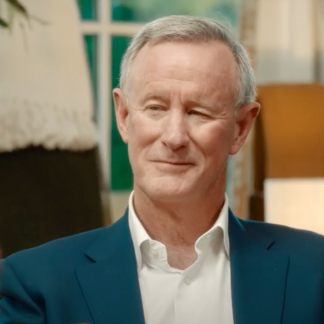 A man wearing a blue suit jacket, listening to someone out of frame