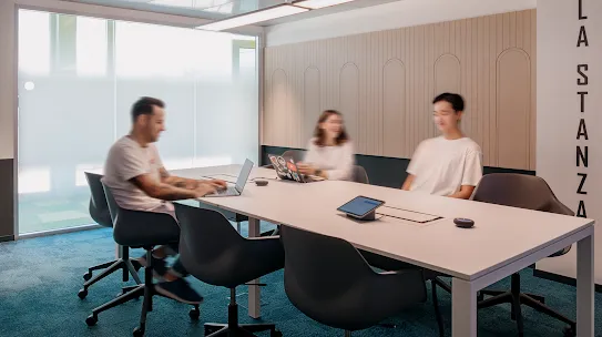 Three people sit together in a conference room.